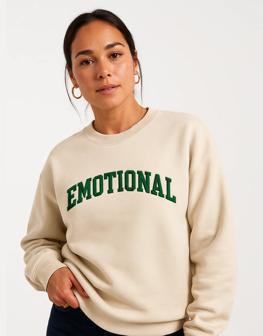 Person wearing a beige sweatshirt with 'EMOTIONAL' in green text on a white background